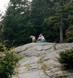 The author and her dog, Sadie, a yellow Labrador, are sitting on a rock during a hike in Maine.