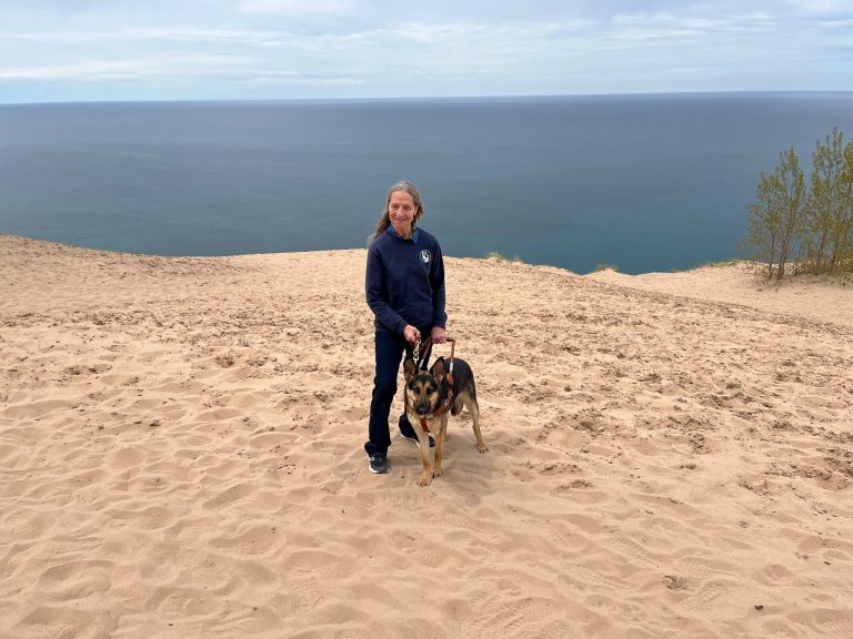 The author and her new dog, Kasey, standing atop a huge sand dune at Sleeping Bear Dunes National Lakeshore with Lake Michigan in the background.