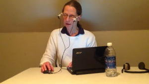 The author, seated at a card table, recording her book, Out of the Whirlpool.