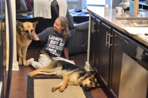 The author sits on the floor with retired Quan and brand new dog, Kasey.